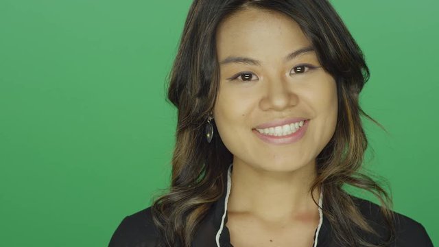 Young Asian woman smiling pleasantly, on a green screen studio background