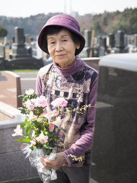 お彼岸にお墓に花を添える80歳の母
