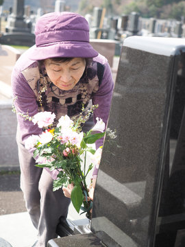 お彼岸にお墓に花を添える80歳の母