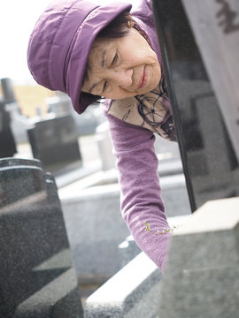 お彼岸にお墓を掃除する80歳の母
