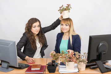 An employee of the office puts on a head-grower colleagues with a flower pot
