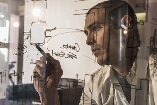 Caucasian businessman writing on glass