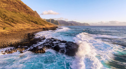 Large waves crashing into rocky outcrop along a mountain side on Oahu's north west shore in Hawaii