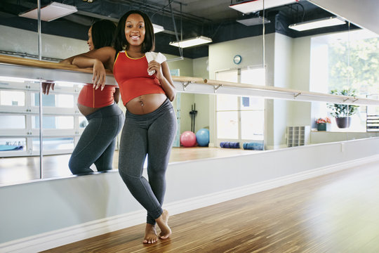 Pregnant Black woman smiling in yoga studio