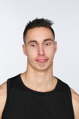 Portrait d'un jeune homme sur fond blanc qui fait des grimaces
