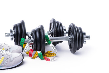 Dumbbells with measuring tape and sneakers on white