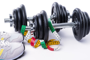 Dumbbells with measuring tape and sneakers on white