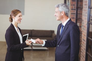 Fototapeta premium Businesswoman giving business card to client in office