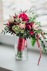 Bride bouquet of wedding flowers red and beige peonies, lily, greenery in vase on white background. color Marsala