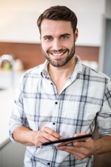 Happy young man using digital tablet in kitchen