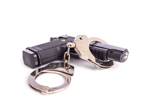 Close up gun and handcuffs isolated on white
