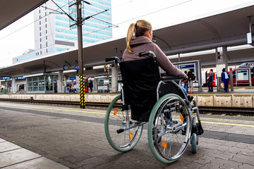 Frau sitzt in einem Rollstuhl auf einem Bahnhof