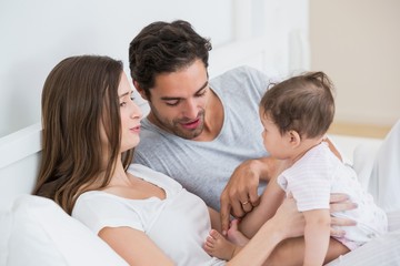 Fototapeta premium Couple playing with baby girl at home