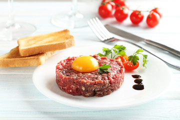 Beef tartare with egg yolk on a blue wooden table