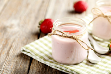 Strawberry yogurt in glass on a grey wooden table