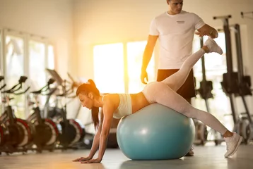 Fotobehang Persoonlijk gym woman with personal trainer man  © luckybusiness