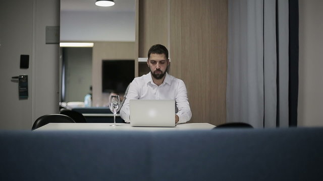 Businessman works at laptop in a hotel room
