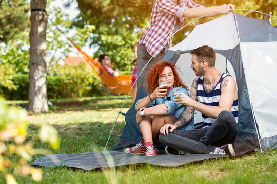 Male and female drinks beer in front of tent