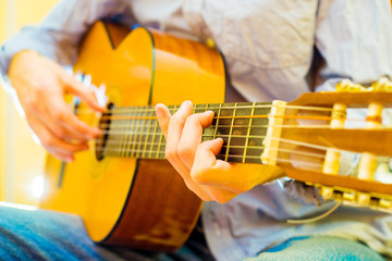 the young guy in jeans are playing an acoustic guitar. Shooting backlit