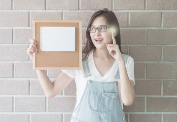 Asian woman with cork board in hand with have an idea face