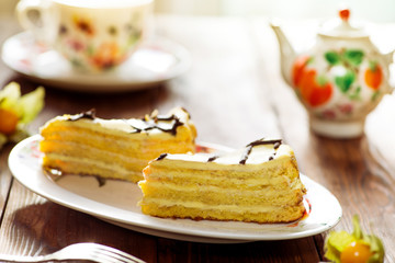 slices of cake with a cream with tea set on a served table
