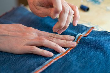 Obraz na płótnie Canvas woman sewing denim. close-up on tools