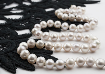 Pearl necklace on white background with black lace
