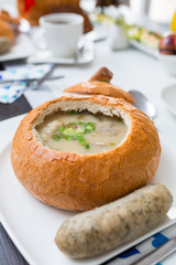 Easter traditional polish breakfast with white borsch soup in bread bowl, eggs and white sausages