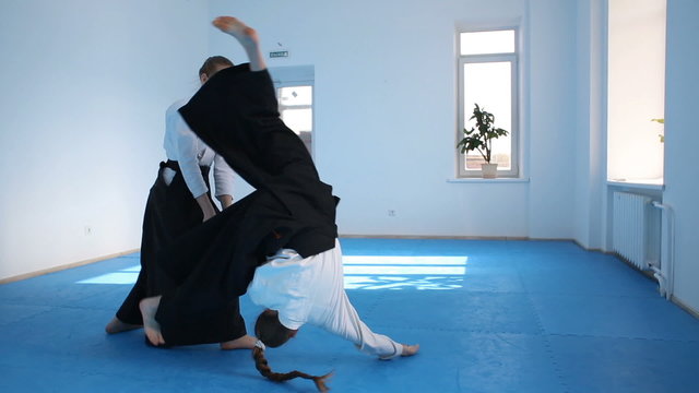 Two girls in black hakama practice Aikido on martial arts training