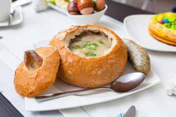Easter traditional polish breakfast with white borsch soup in bread bowl, eggs and white sausages