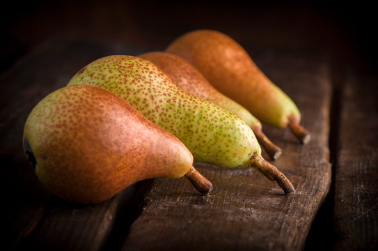 Pears close up group on old brown wooden table and dark background in studio