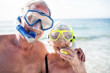 Happy senior couple with their diving mask at beach 