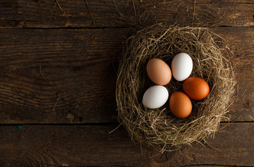 Fresh chicken eggs in a nest on a wooden background