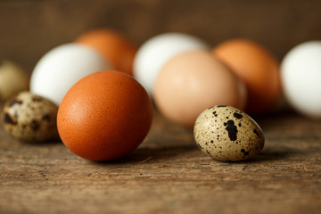 Fresh chicken and quail eggs on a wooden background