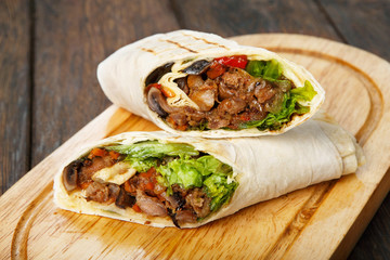 Burrito with pork meat and vegetables at wood desk - obrazy, fototapety, plakaty