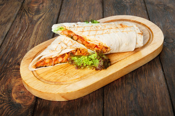 Burritos with chili con carne at wooden desk