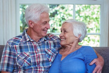 Senior couple looking at each other while sitting on sofa