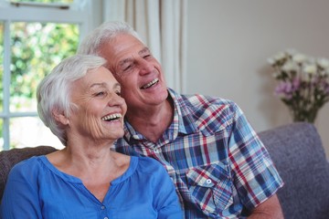 Senior couple looking away while sitting on sofa