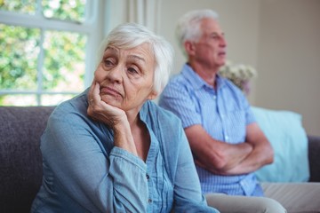 Senior couple after arguing while sitting on sofa 