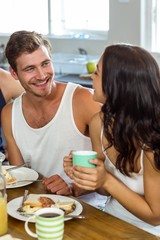 Obraz na płótnie Canvas Man looking at woman while having breakfast at home