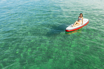 Fototapeta premium Woman relaxing over a paddle surfboard