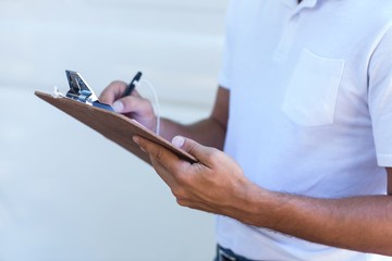 Midsection of delivery man writing in clipboard 