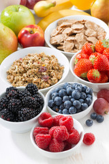 fresh berries, fruit and muesli for breakfast on wooden table