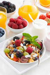 fruit salad in a bowl and various yoghurt, vertical, top view