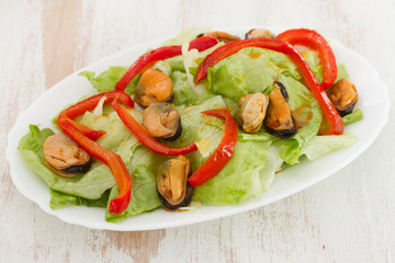 salad with mussels on white dish on white wooden background