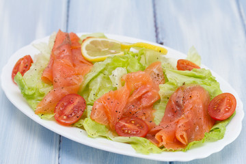 salad with smoked salmon on white dish on blue background