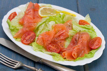 salad with smoked salmon on white dish on blue background