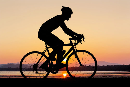 Man silhouette cycling at beach
