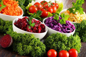 Composition with four vegetable salad bowls on wooden table