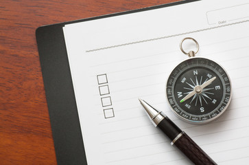 Concept : pen and compass on book with checklist box with wood background